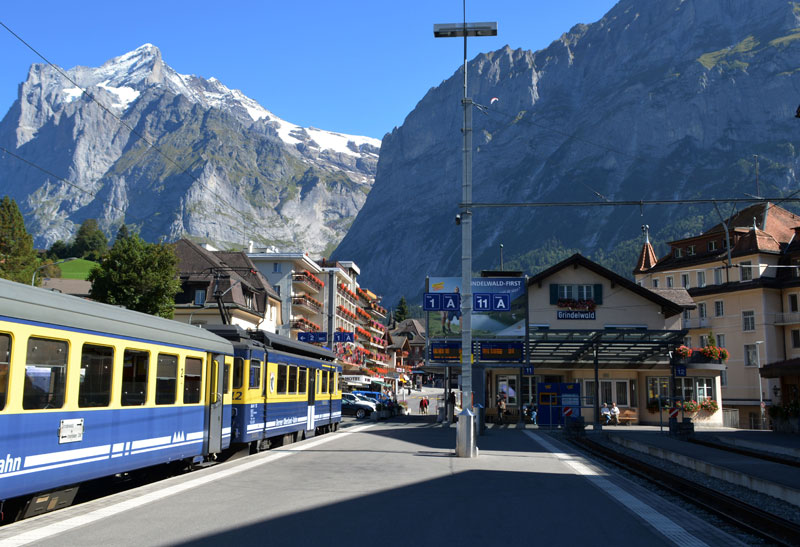 train at the platform at Grindelwald station with mountains behind