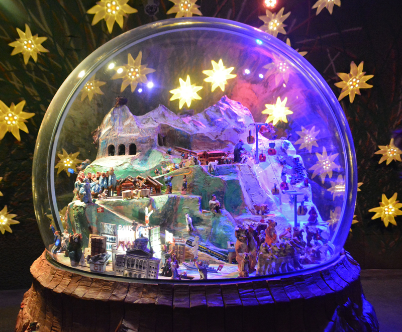 giant snow globe containing winter alpine scene surrounded by gold stars