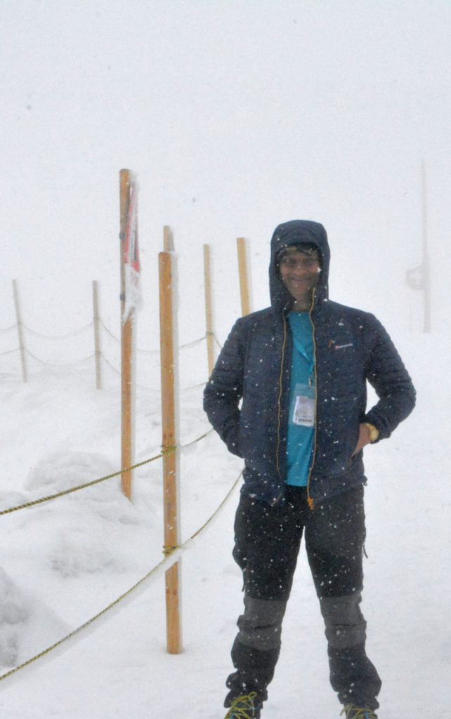 man standing next to wooden poles in snow