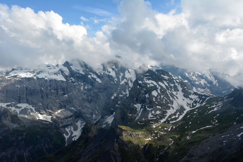 view of snow capped mountains with clouds over summits