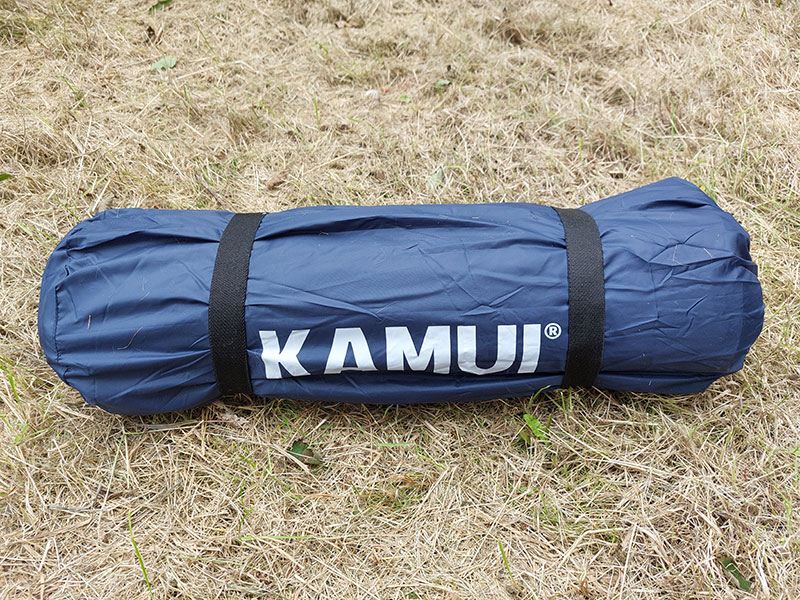 Dark blue Kamui sleeping mat rolled up on dried grass