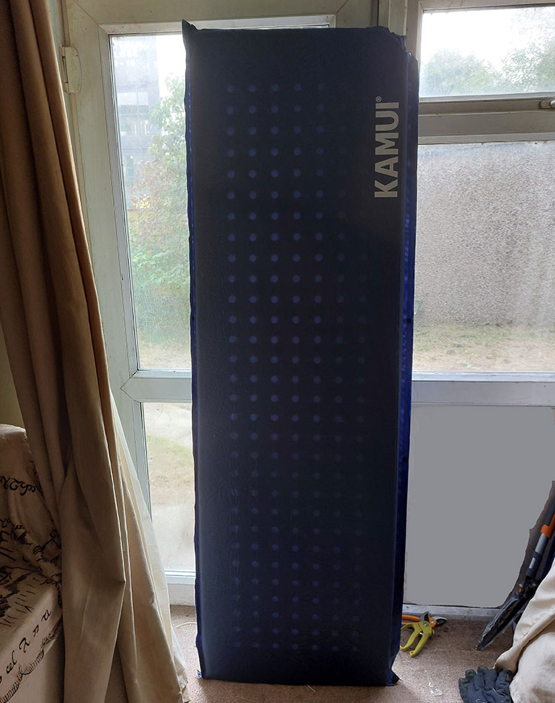 Dark blue Kamui sleeping mat standing upright by a doorway