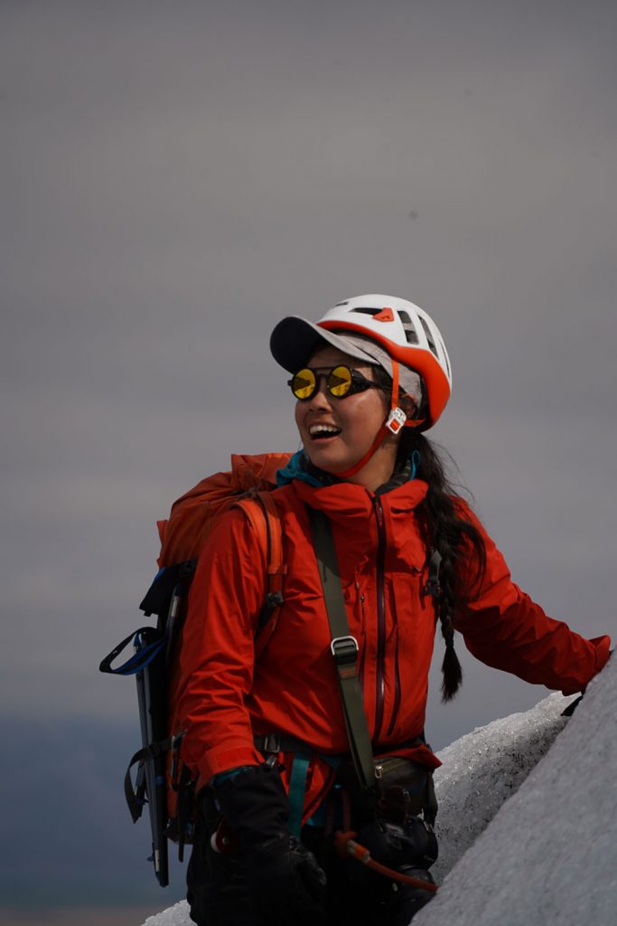 Female climber in red jacket, white helmet and Vallon Heron Glacier Glasses in Iceland
