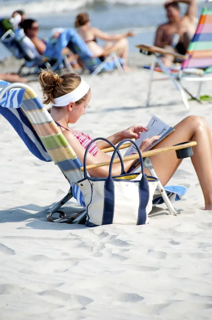 gil on a deckchair on the beach reading a magazine
