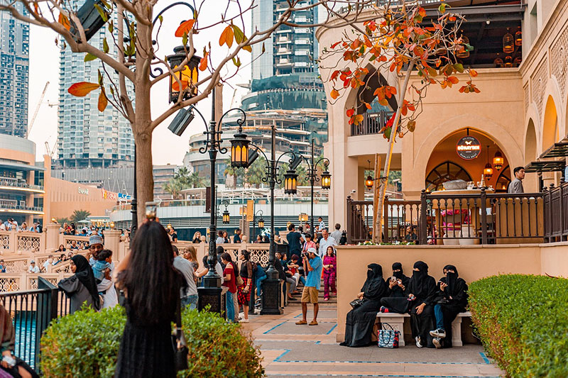 Downtown Dubai. People on a busy city street with autumn leaves on trees