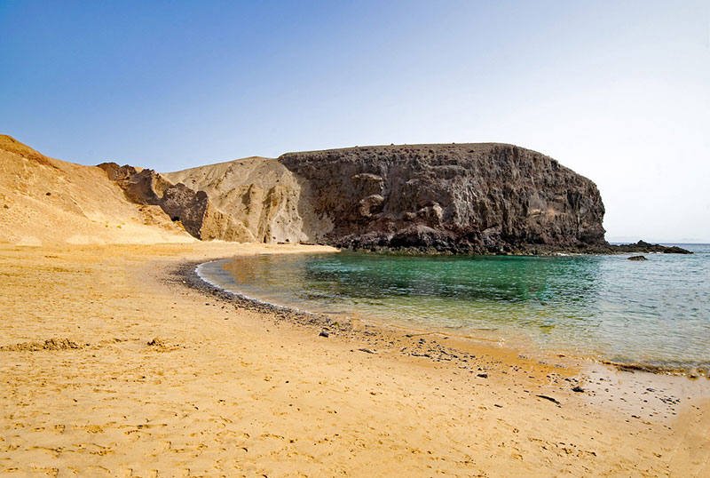 sea and sand. a beach next to a cliff headland reaching out into the sea bathed in winter sun